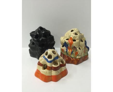 A Clarice Cliff Flower Frog decorated in the Crocus design together with a Clarice Cliff Fantasque Flower Frog and a black gl