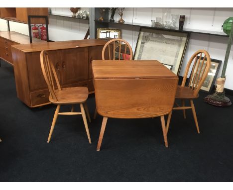 An Ercol Windsor Light Finish dining room suite comprising a three door sideboard, rectangular drop-leaf table and three chai