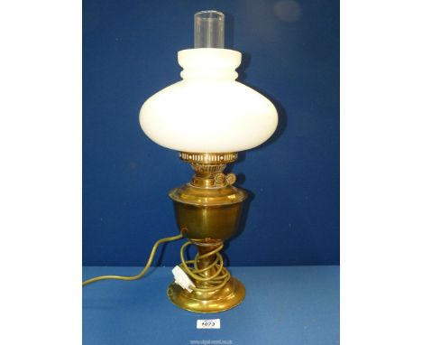 A brass oil lamp (converted to electric) with chimney and white shade.