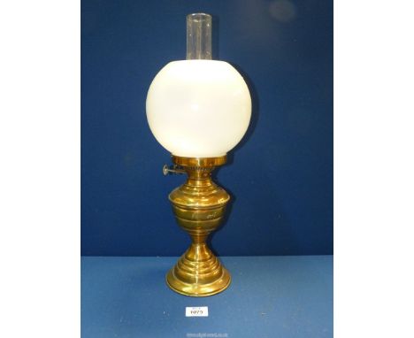 A Brass oil Lamp with chimney and white globe glass shade.