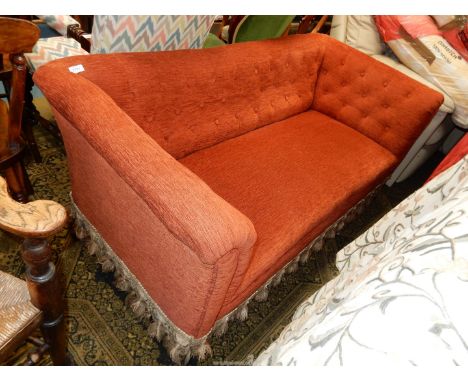 A likely Edwardian two/three seater Sofa re-upholstered in buttoned rust coloured fabric and standing on turned front legs.