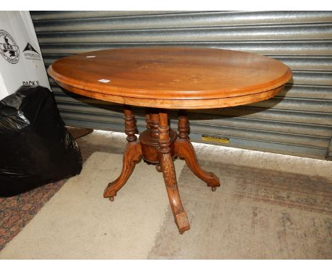 A mixed woods snap-top oval topped Loo type Table having contrasting inlaid decoration to the top, raised on four turned pill