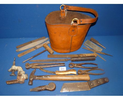  A leather bucket containing a selection of vintage farrier's tools, bucket measures approx. 8 1/2" diameter x 8 1/2" high.