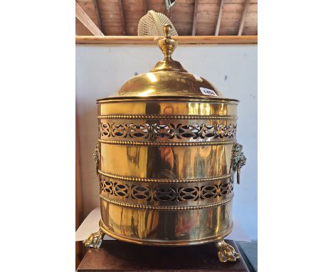 A brass coal bucket with pierced sides and flanking lion mask ring handles, set on lion paw feet - no liner