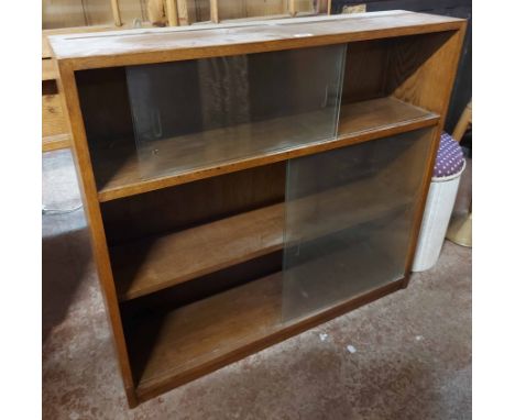 A 92cm vintage oak three shelf bookcase enclosed by sliding glass doors