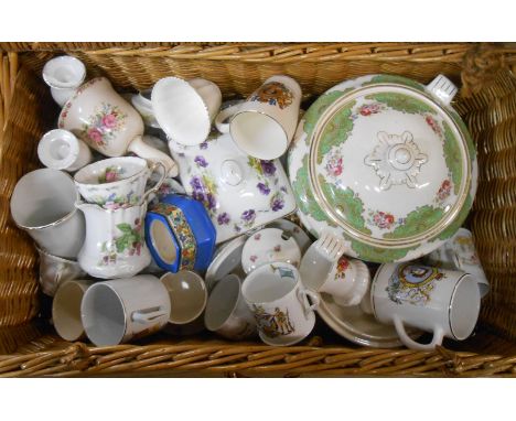 A wicker hamper containing a quantity of ceramics including commemorative mugs, etc.