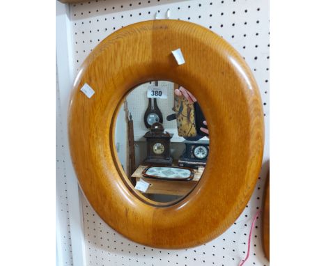 A wide oak framed oval wall mirror with easel back
