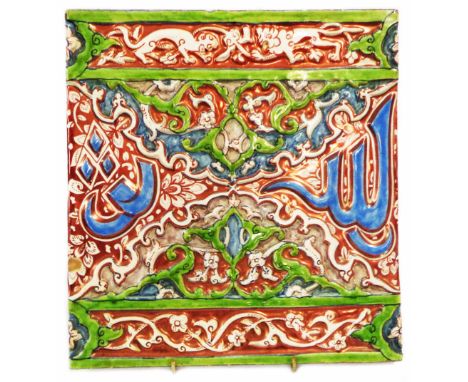 A large antique Islamic tin glazed tile with moulded decoration depicting script amidst foliage scrolls with an animal border