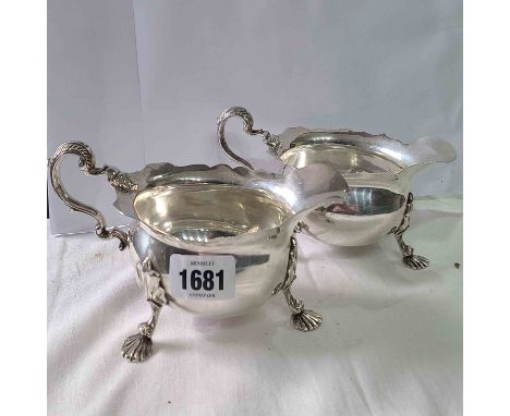 A pair of Mappin &amp; Webb silver sauce boats with cast C scroll handles, set on shell pattern feet - Sheffield 1902 and 190