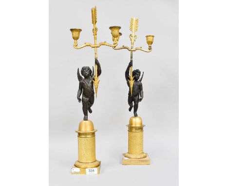 A Pair of Regency Gilt Metal and Patinated Bronze, twin light candleabra in the form of Cupid, holding aloft an arrow, on an 
