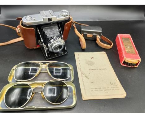 A tray containing vintage sunglasses and zeiss ikon nettar camera. 