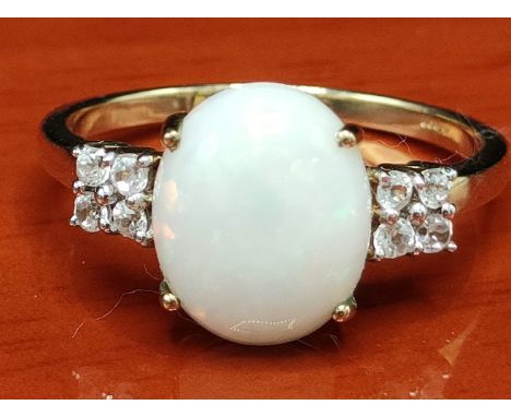 10ct yellow gold  ring set with a large White Australian Opal off set by white spinel stone shoulders. [Ring size R] [2.79Gra