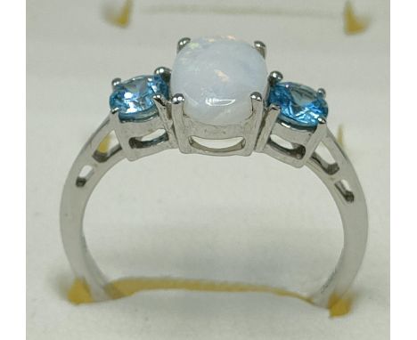 10ct white gold ring set with an oval cut opal stone off set by blue topaz stones to each shoulder. [Ring size N] [2.32Grams]