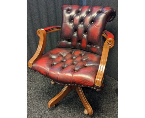 Reproduction oxblood red chesterfield arm chair, the back with button detail and brass nail head trim raised on a swivel base