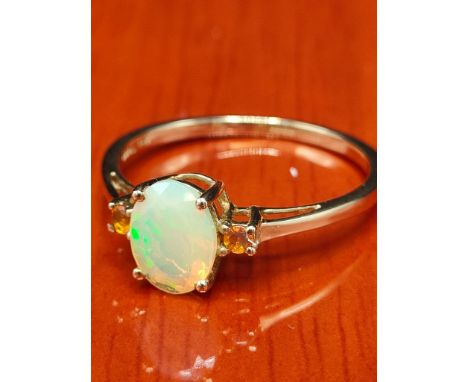 10ct yellow gold ring set with an Ethiopian opal stone off set by two orange stones. [Ring size R] [1.84Grams] 