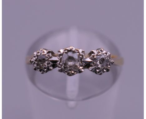 An 18 ct gold and platinum three stone diamond ring. Ring size J/K. 2.3 grammes total weight.