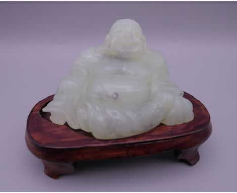 A jade model of Buddha on a wooden stand. 6.5 cm high overall.