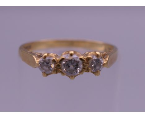 An 18 ct gold three stone diamond ring. Ring size J/K. 2 grammes total weight.