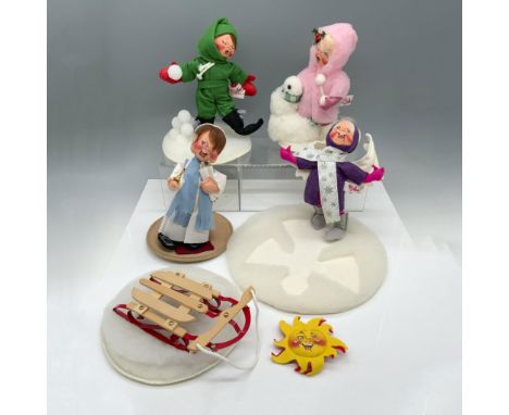 Gorgeous collection of dolls that includes a child in a green outfit making snowballs, a child in a fluffy pink jacket making