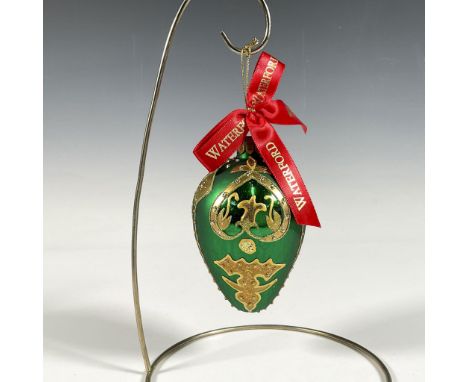 Handcrafted ornament adorned with gold decorative elements that include holly leaves and a stylized fleur de lis crown. The s
