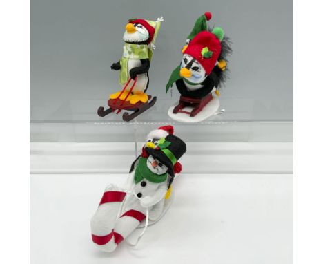 Adorable set of Winter figures that includes a penguin wearing a holiday hat topped with a snowflake, a snowman riding a cand
