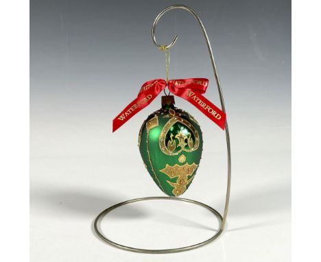 Handcrafted ornament adorned with gold decorative elements that include holly leaves and a stylized fleur de lis crown. The s