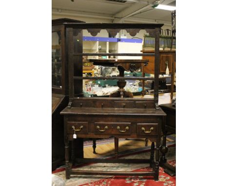An early 18th Century oak dresser and rack, the rack with three fitted plate shelves and four spice drawers, the base section