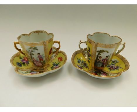 Two Dresden quatrefoil twin-handled chocolate cups and saucers, with two yellow ground panels painted with floral sprays and 