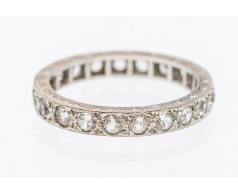 A stone set white metal eternity ring, width approx 3mm, size K1/2, unmarked, engraved mount, total gross weight approx 2.3gm