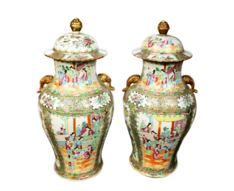 A pair of late 19th century Cantonese famille rose lidded vases, with elephant trunk handles and extensive floral and foliage