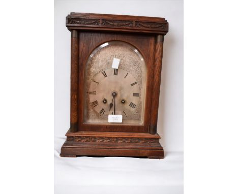 A 19th Century oak eight day mantle clock with silvered arched dial and Roman numerals.