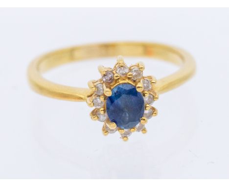 A sapphire and diamond 18ct gold cluster ring, set with an oval mixed cut sapphire approx 5x4mm, claw set within a diamond se