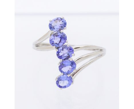 A tanzanite and 9ct white gold ring, comprising a row of five oval mixed cut stones, claw set to a three row split shank, wid