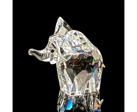 A clear faceted elephant with ears out, trunk up, frosted tail, and black crystal eyes. Swarovski mark. This item has its ori