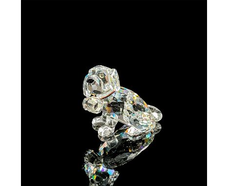 A clear faceted dog figure with tawny eyes, black nose, and elastic collar holding the keg. Swarovski mark. This item has its