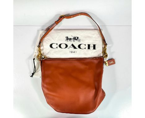 Glovetanned bag with tassel pull on zipper top closure. Coach carriage tag attached to side metal ring. Fabric interior has z