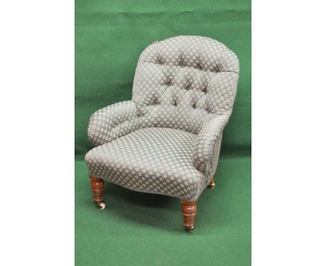 Victorian button back armchair having arched top, padded arms and over stuffed seat with shaped front, standing on turned leg