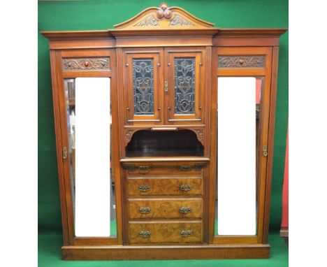 Walnut triple breakfront wardrobe having moulded and carved cornice over two central leaded light doors opening to reveal fix