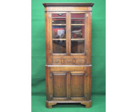 Bespoke made oak corner cupboard having dentil cornice over two glazed doors opening to reveal two fixed shelves above three 