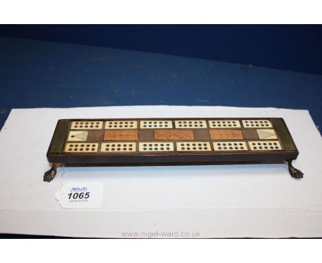 An antique mixed wood and ivory Cribbage Board with pegs, standing on four paw feet