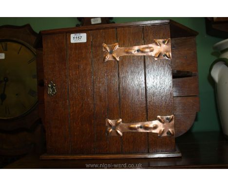 An Oak Smoker's Cabinet with door opening to reveal two shelf compartment and two puce rack shelves to either side