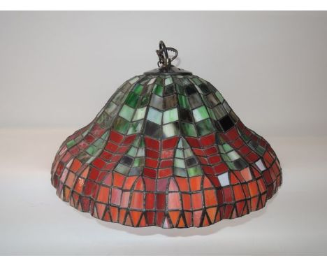 A ceiling hanging leaded glass light shade in the Tiffany manner in tones of mottled green and red