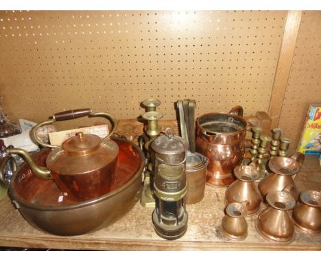 An extensive collection of brass and copper wares to include a substantial copper pan with applied brass handles, a graduated