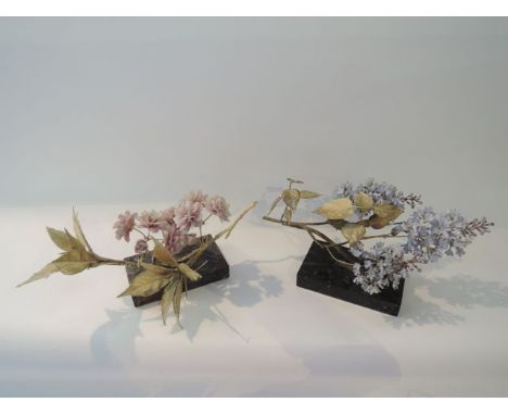A pair of ceramic and cast metal naturalistically modelled groups of blossom and lilac, both raised on rectangular marble typ