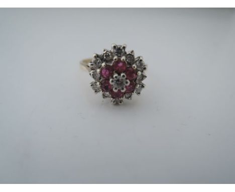 A diamond and ruby cluster ring, centred with a round brilliant-cut diamond weighing approximately 0.04cts, within a surround