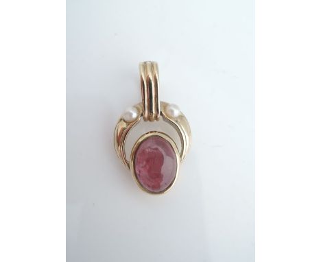A ruby and pearl pendant clasp, set with an untested cabochon ruby, highlighted above with two pearls, in unmarked gold