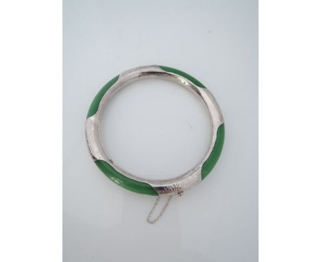 A jade hinged bangle, mounted with sterling silver details, with safety chain