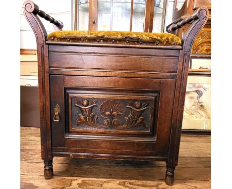 A Victorian piano stool with handles, mustard velvet upholstery, and a carved panel on the door concealing a shelf inside the