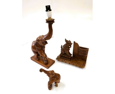 Three wooden ornaments including an elephant lamp, a baby elephant , and a Burmese style lion.
