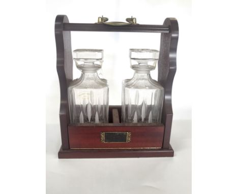 A mahogany double tantalus with brass handle and drop front  (32cm x 27cm x 15cm), containing a pair of square cut glass spir
